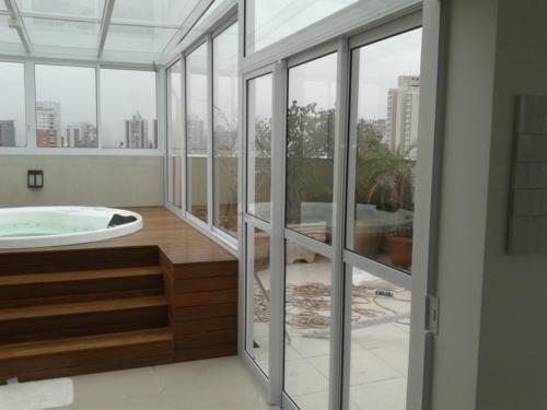 Fechamento de todo ambiente com estrutura em alumínio branco, utilizando vidro incolor